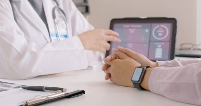 image of docor and patient with a smartwatch and ipad on table