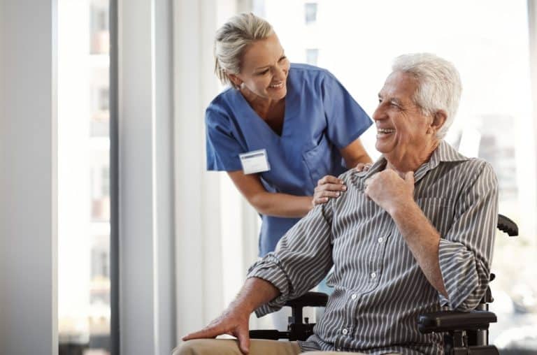 elderly man in wheelchair supported by nurse